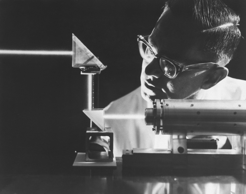 An intense ruby laser light beam penetrates twin prisms during an experiment at North American Aviation’s Autonetics Division, 1965. Despite the brilliance of the beam laser weapons were still a half century from reality.